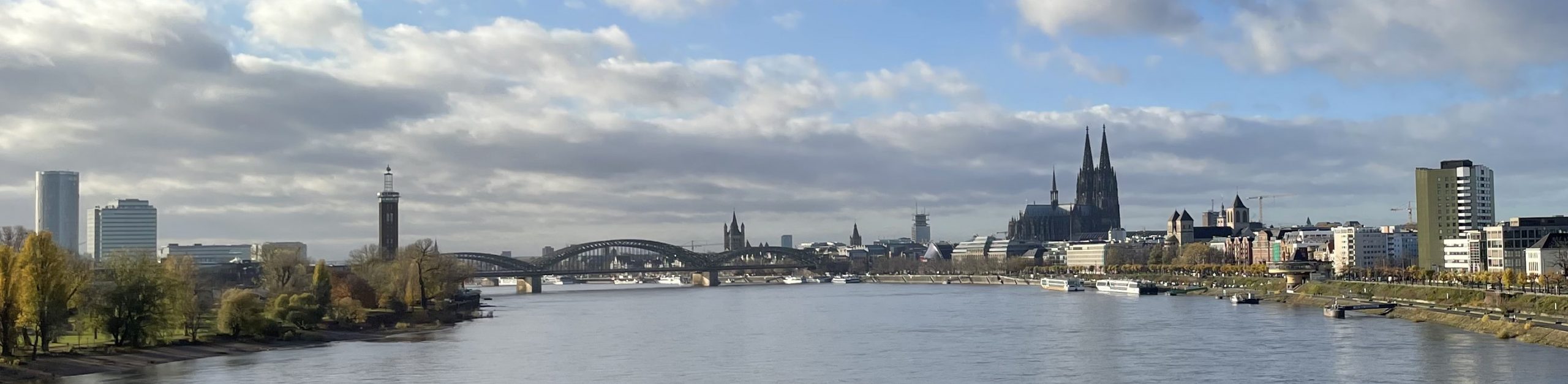Hohenzollernbrücke Köln mit Rheinpark und Kölner Dom vom Fluß aus gesehen